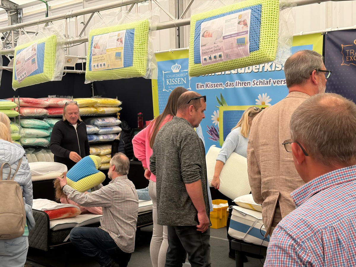 Voller Schlafzauber-Messestand: Besucher probieren Kissen, im Hintergrund die Kissenwand