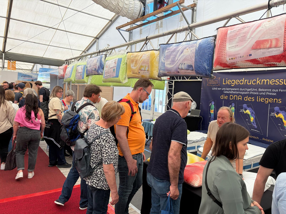Besucher am Messestand unter der Reihe bunter Schlafzauber-Kissen