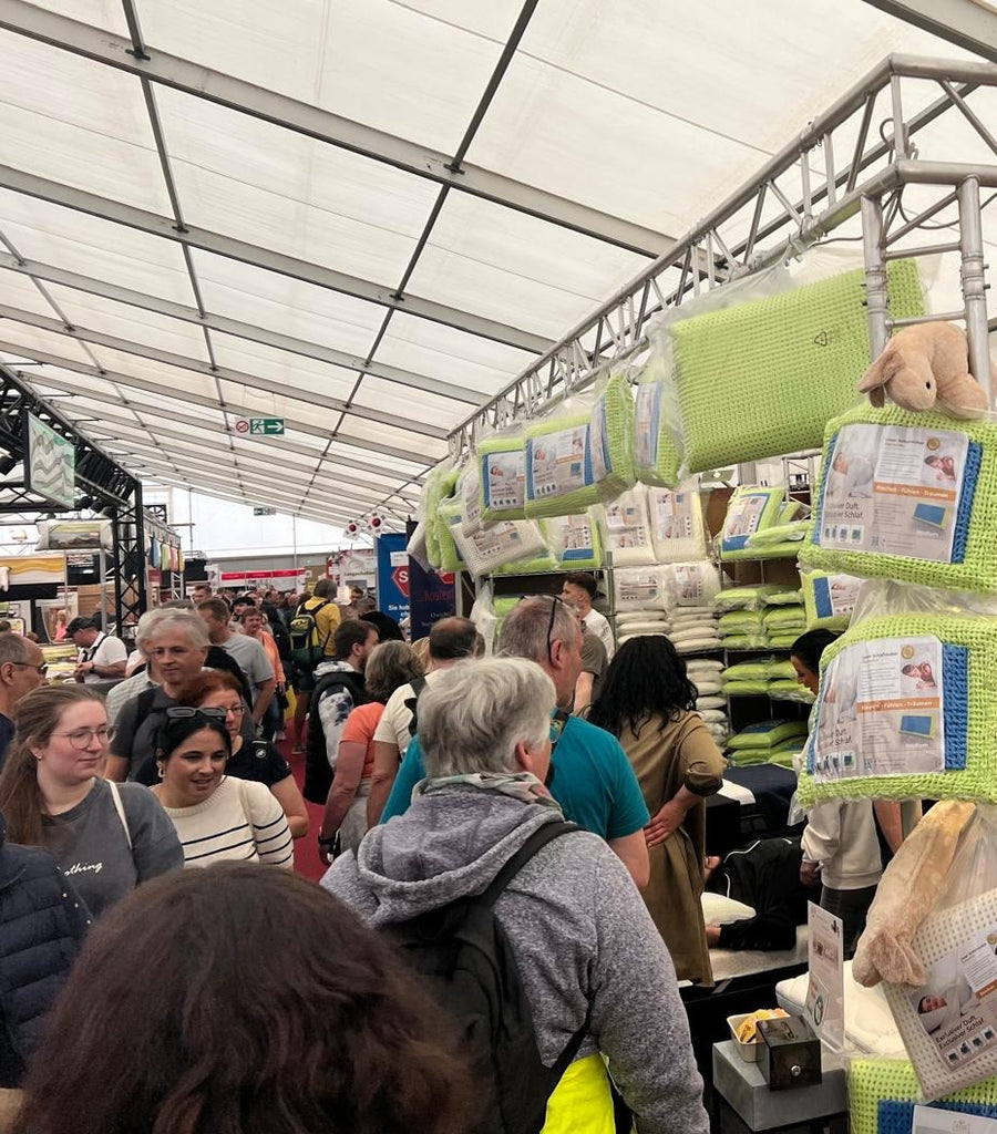 Gut besuchter Schlafzauber-Messestand mit Besuchern vor der Kissenauswahl
